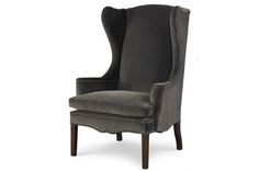 an upholstered grey chair with studding on the legs and back, against a white background