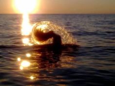 a person swimming in the ocean at sunset