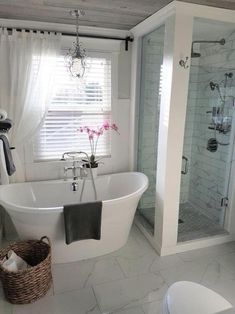 a white bath tub sitting under a window next to a toilet and shower stall in a bathroom