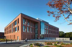 a brick building with lots of windows on the side of it and a man walking in front of it