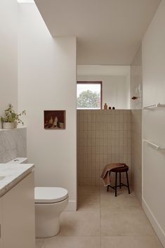 a bathroom with a toilet, sink and tiled walls in it's own area