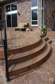 a wooden deck with steps leading up to the front door and patio furniture in the background