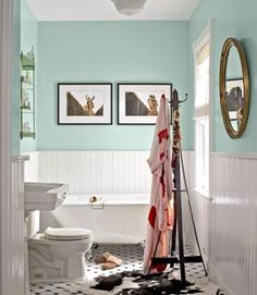 a bathroom with two pictures on the wall and a bathtub in the corner,