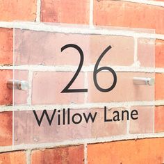 a brick wall with the number 26 on it's side and an address sign that reads willow lane