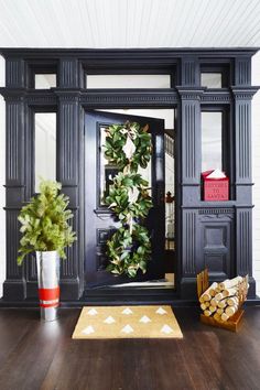 the front door is decorated in black and features a wreath, potted plant, and fire extinguisher