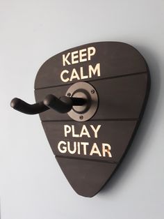 a guitar pick with the words keep calm and play guitar on it's side