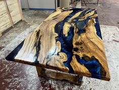 a wooden table sitting on top of a white floor covered in blue and gold paint