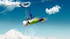 a man flying through the air while riding a zip line in front of a mountain