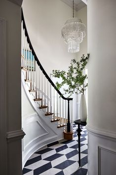 a foyer with black and white checkered flooring, chandelier and stairs