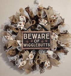 a wreath that says beware of wigglebutts hanging on the wall