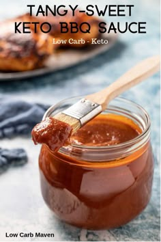 a jar filled with keto bbq sauce on top of a table next to a wooden spatula