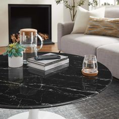 a black marble coffee table in a living room with a white couch and fireplace behind it