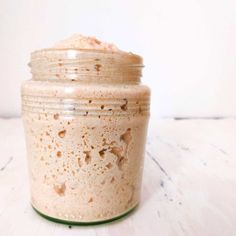 a glass jar filled with food sitting on top of a wooden table next to a white wall