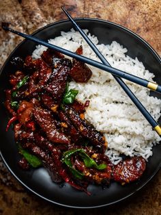 rice and meat with chopsticks on a black plate