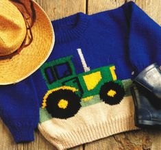 a blue sweater with a green tractor on it and a cowboy hat next to it