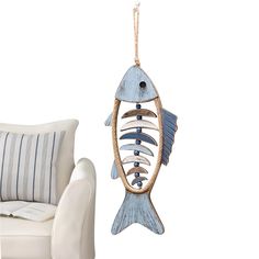 a blue fish hanging from a rope next to a white chair with pillows on it