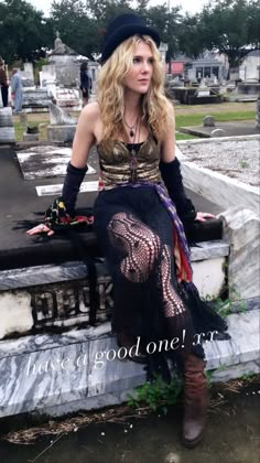 a woman sitting on top of a grave wearing a black hat and dress with lace