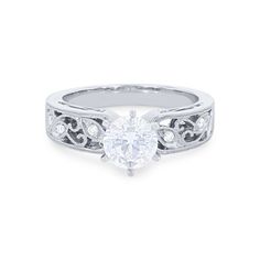 a white gold engagement ring with a heart shaped diamond in the center and filigrees around the band