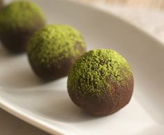 three chocolate balls covered in green sprinkles on a white plate