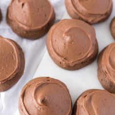 chocolate frosted cupcakes sitting on top of white paper