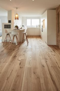 an open kitchen and dining room with wood flooring, white walls and wooden floors