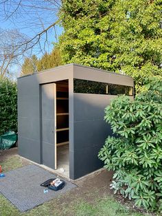 an outdoor storage shed in the middle of a garden with trees and bushes around it