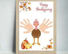 a thanksgiving card with a turkey and handprints on it, next to a pumpkin