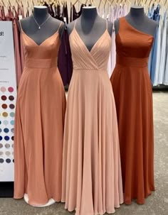 three bridesmaid dresses are on display at the bridal shop, one is peach