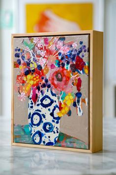 a vase with flowers painted on it is sitting on a table next to a painting