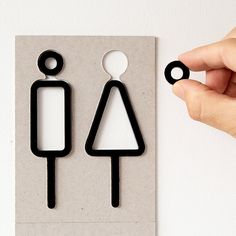 a pair of black earrings is being held by a person's hand over a piece of paper