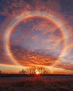 the sun is setting and it looks like a ring in the sky over an open field