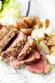 meat, potatoes and lettuce on a plate with some seasoning next to it