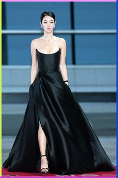 a woman in a black dress walking down a runway