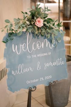 a welcome sign sitting on top of a metal stand next to a potted plant