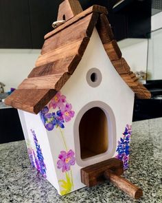 a birdhouse made out of wood and painted with flowers on the outside, sitting on a kitchen counter