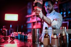 a bartender is pouring a drink into a glass at the bar stock - fotor