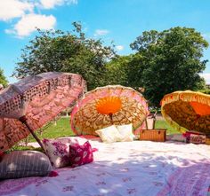 three decorative umbrellas sitting on top of a bed covered in blankets and throw pillows