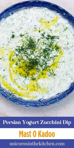 a blue bowl filled with white sauce and topped with green garnish on top