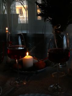 two glasses of wine on a table with candles