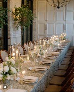 a long table is set with white flowers and candles for an elegant dinner party or reception