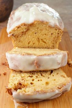 two glazed donuts sitting on top of a cutting board next to a loaf of bread