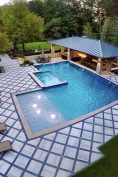 an aerial view of a swimming pool with lounge chairs around it and trees in the background