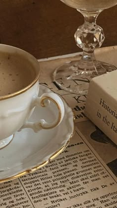 a cup of coffee sitting on top of a saucer next to an open book