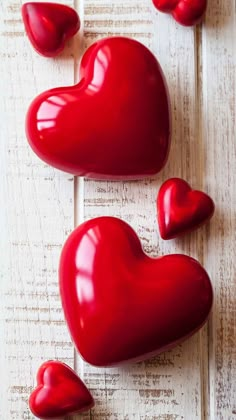 red heart shaped candy sitting on top of a white wooden table next to other hearts