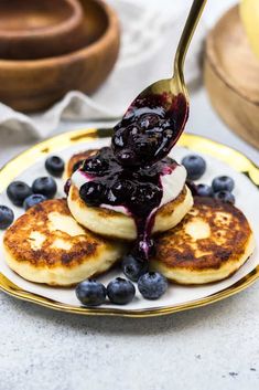 blueberry russian cheese pancakes on a plate with syrup being drizzled over them