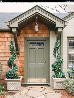 two planters on either side of the front door of a house with green doors