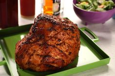 a piece of meat sitting on top of a green tray next to a bowl of salad