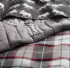 a blanket with horses on it laying on top of a plaid bed sheet and pillow