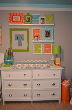 a baby's room with pictures on the wall, dresser and crib in it