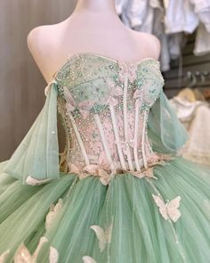 Step into a magical world with this enchanting sage green quinceanera dress that brings a whimsical touch to your celebration. This dress is designed in a classic ball gown silhouette and flows in layers of delicate tulle, creating a full, ethereal skirt that sweeps into a graceful chapel train. The off-the-shoulder neckline adds a touch of romance, beautifully framing your shoulders and neckline. The Intricate appliques and subtle beading embellish the bodice and skirt, while delicate butterfly Light Green Quinceanera Dresses, Sage Green Quinceanera, Quinceanera Dresses Green, Green Quince Dress, Tulle Princess Dress, Dress With Butterflies, Green Quinceanera Dresses, Xv Dresses, Quinceanera Themes Dresses